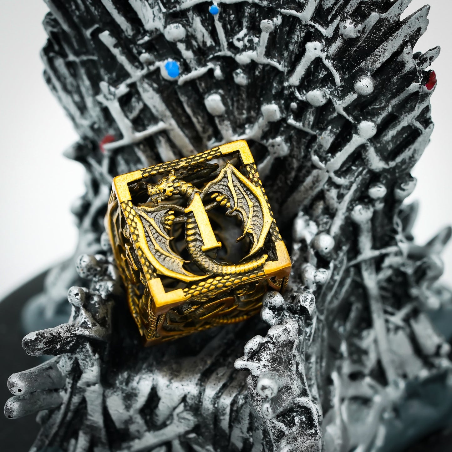 Hollow gold dragon D6 die displayed on fantasy iron throne-style base