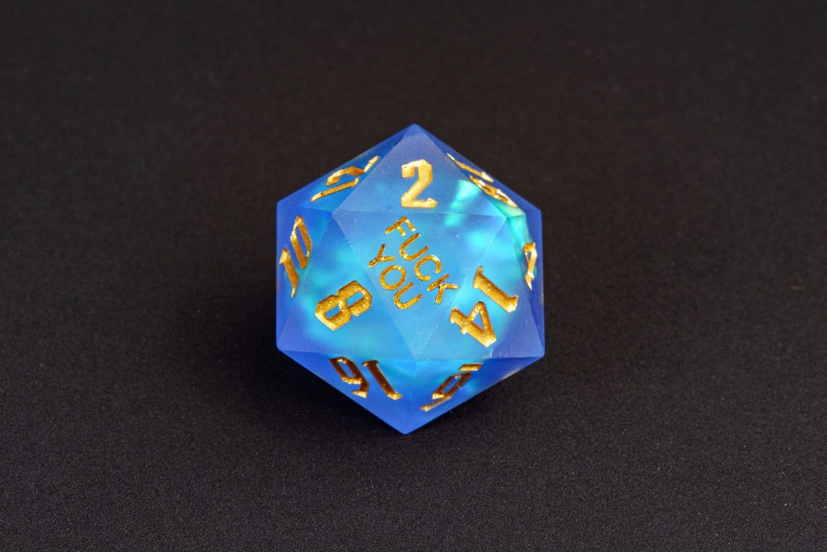 Azure Abyss sharp-edge D20 from the Fck Me Dice Set, translucent blue resin with gold numbering and 'Fck You' lettering