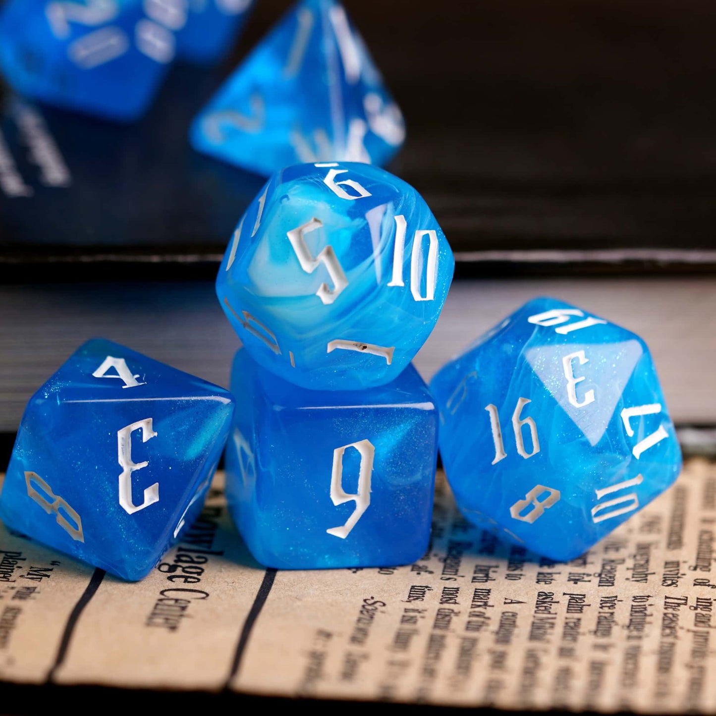 Blue Ice Dice Set resin polyhedral dice stacked on book for DnD and roleplaying games