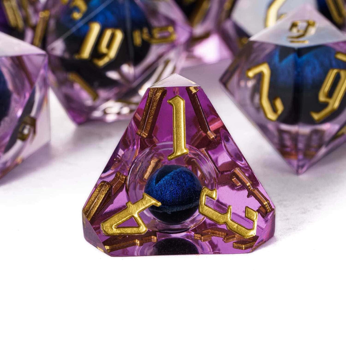 Close up of purple Dragon Eye D4 sharp edge die with gold numbers and suspended blue eye core