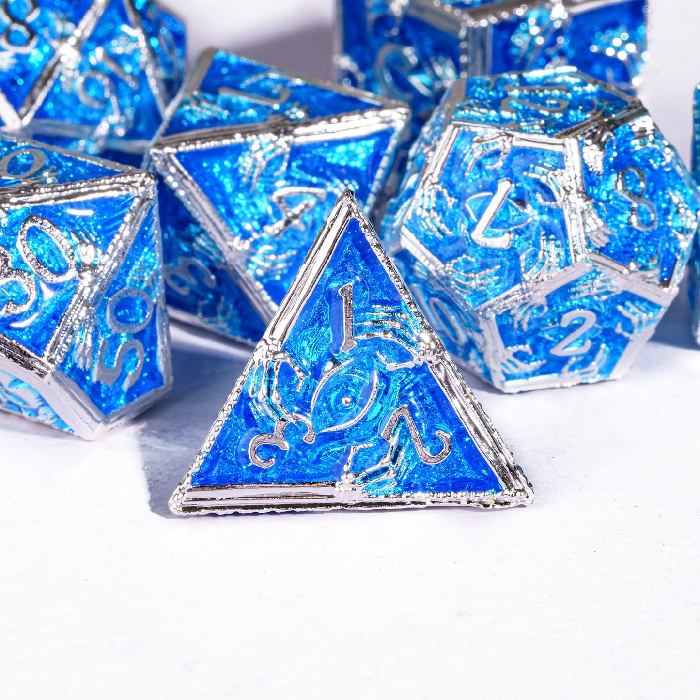 Frosted Crypt Metal Dice Set closeup of blue and silver D4 die with engraved detail