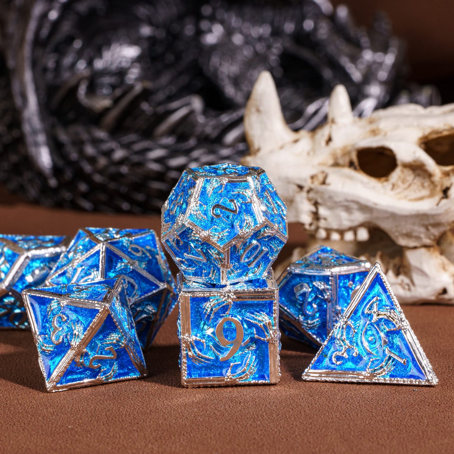 Frosted Crypt Metal Dice Set shimmering blue and silver dice grouped with skull background