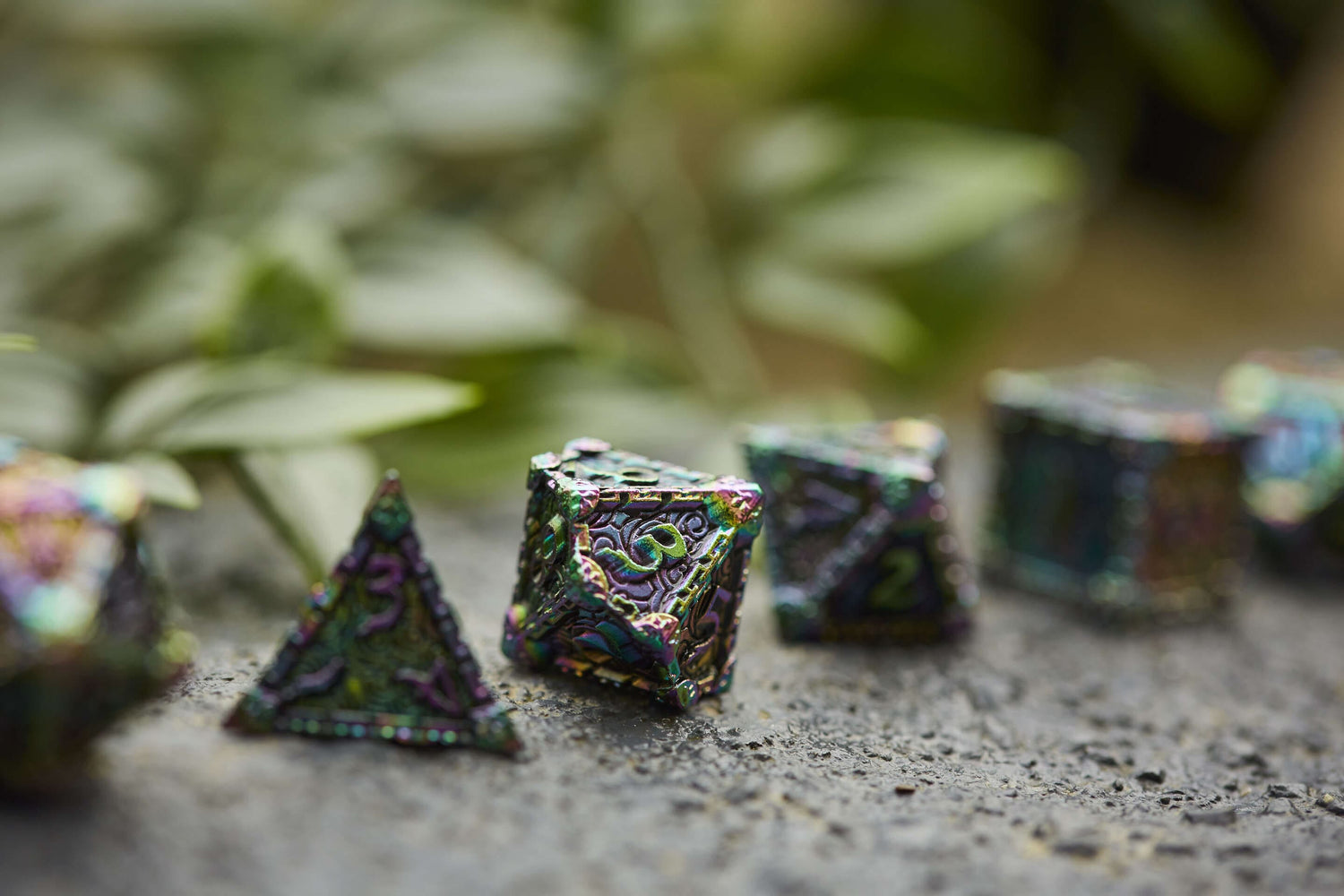 Colorful iridescent metal dice set on a textured stone surface, featuring engraved details for D&D and fantasy RPGs.