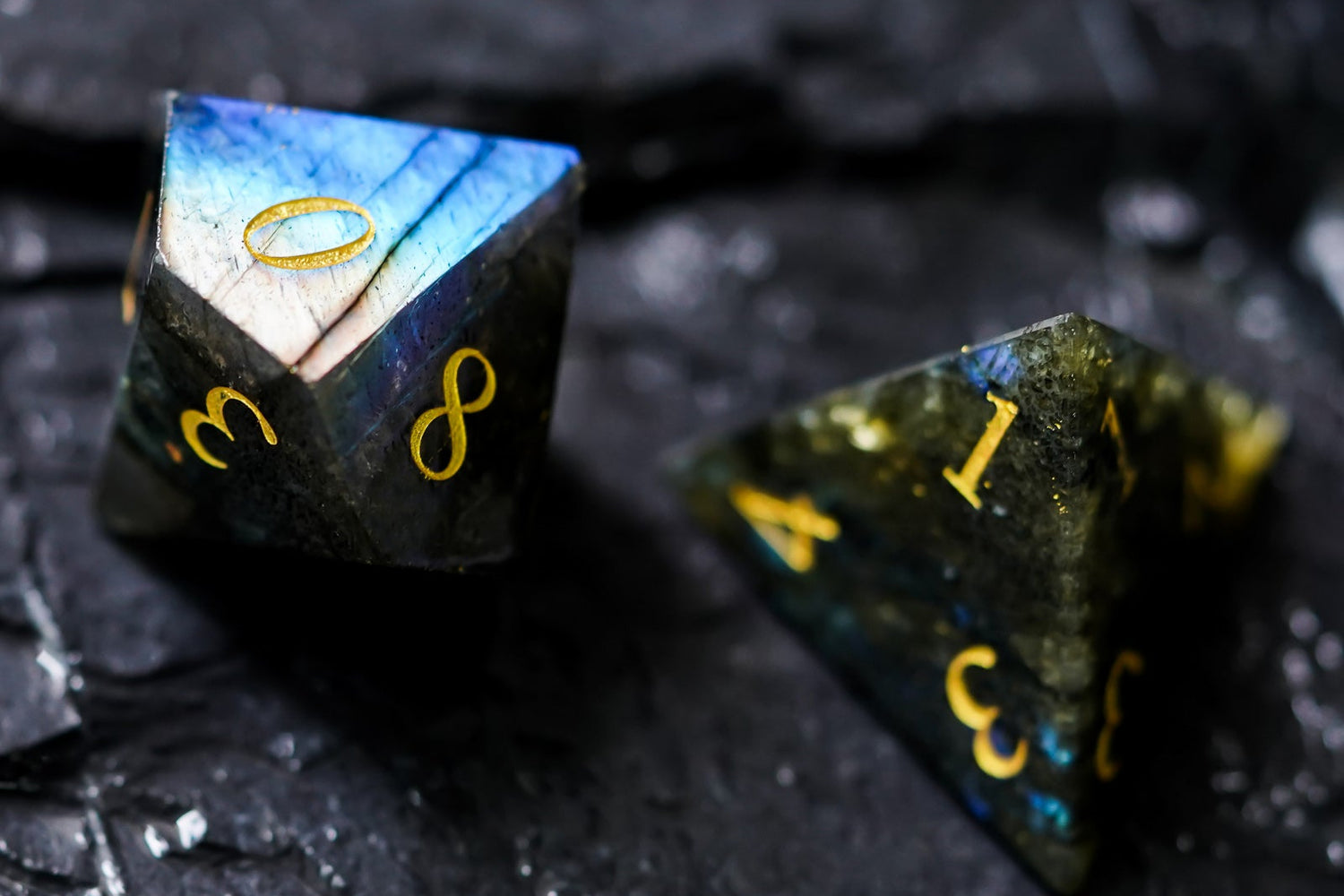 Close-up of labradorite D8 and D4 dice with multicolor flash and sharp edges, perfect for fantasy RPG gaming.
