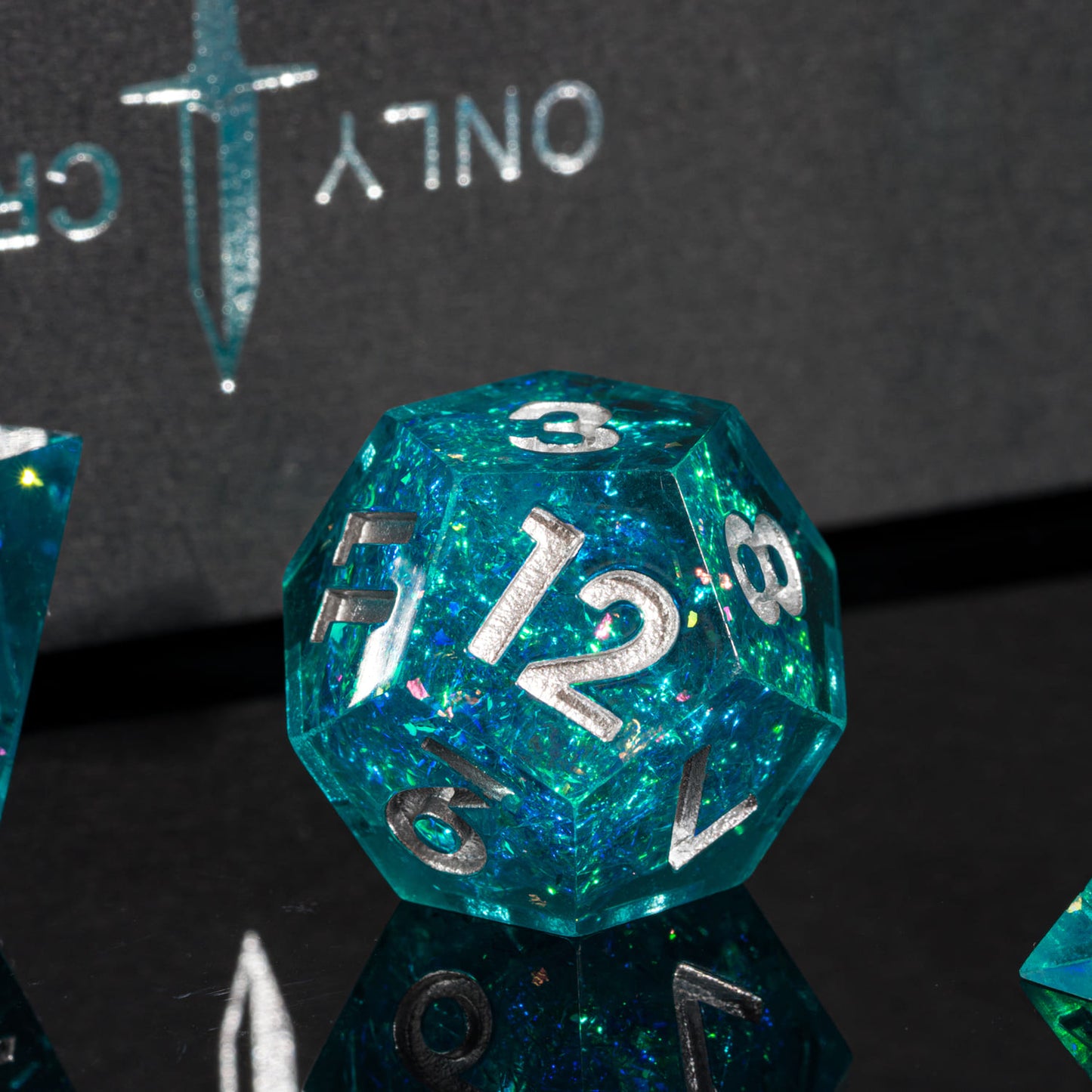 Closeup of Icy Shard d12 dice for DnD and RPG, teal resin with silver numbers and foil detail