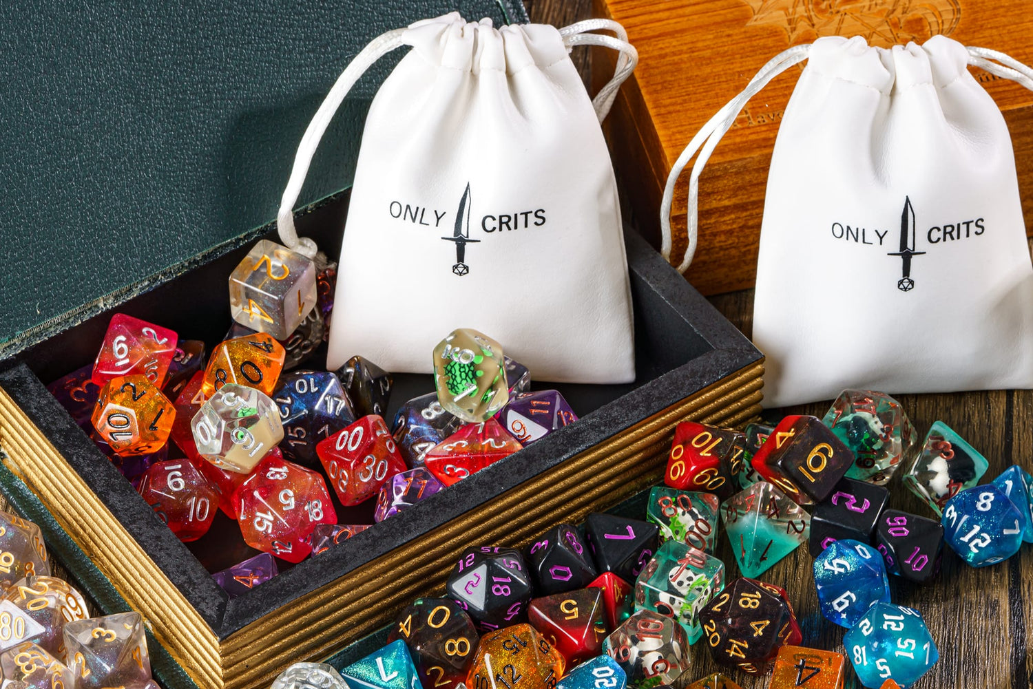 Open dice tray overflowing with random DND dice sets and Only Crits drawstring bags, surrounded by collectible polyhedral dice.