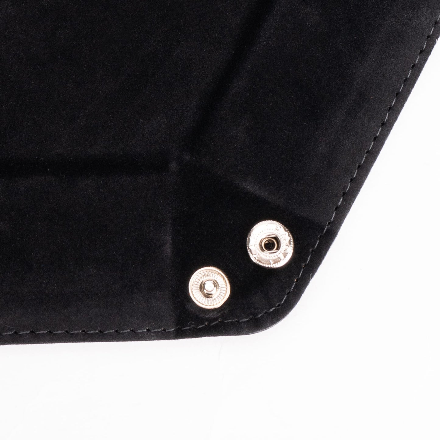 Close-up of metal snap buttons on black hexagon dice tray corner