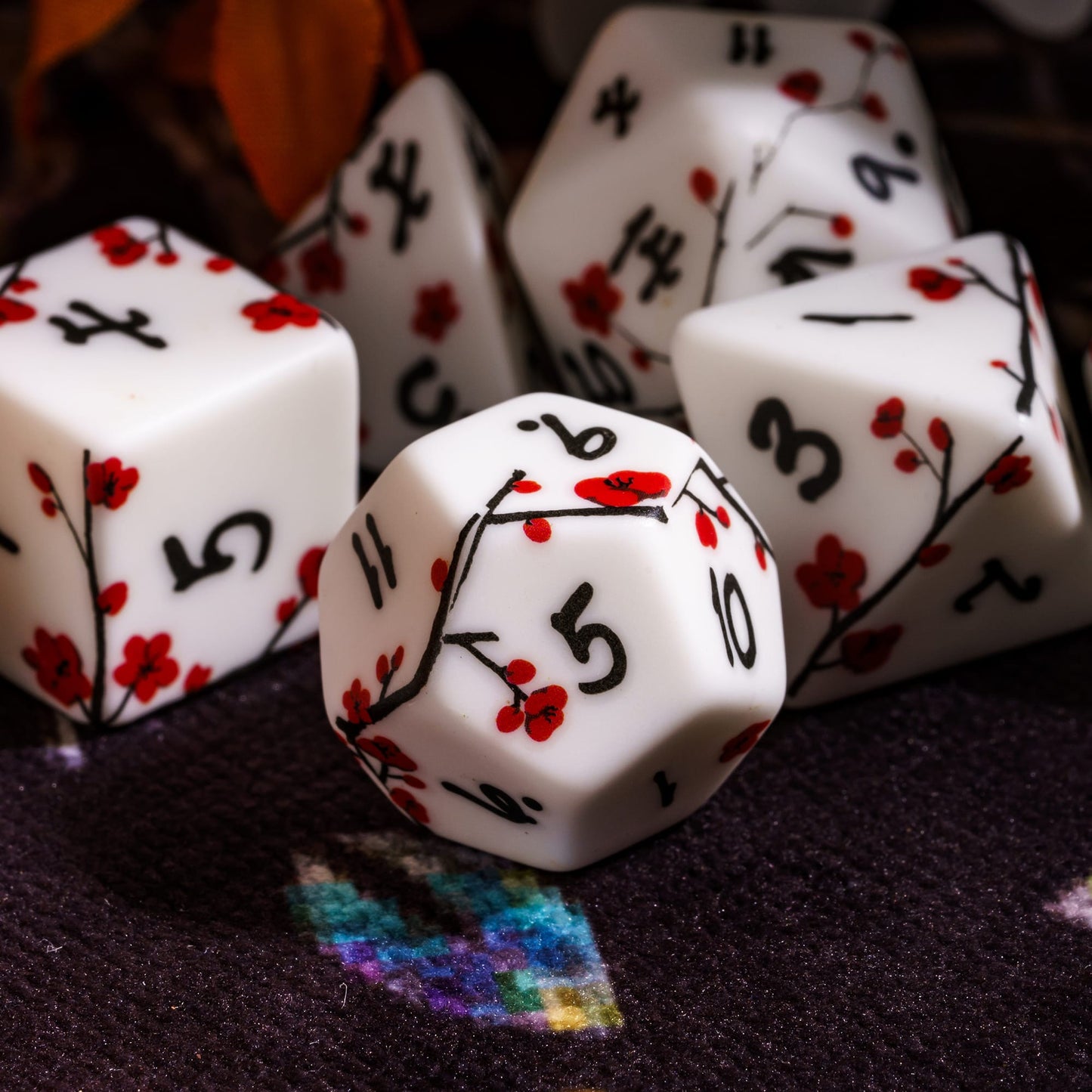 Closeup group of Plum Blossom Dice Set with white base and red blossoms for DnD & DnD 5e