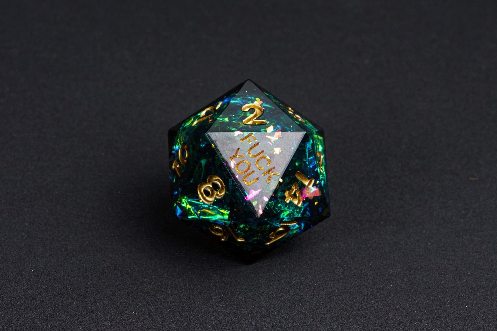Supernova Remnant sharp-edge D20 from the Fck Me Dice Set, deep black resin with gold numbering and 'Fck You' lettering