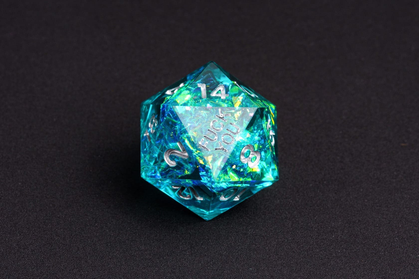 Turquoise Soul sharp-edge D20 from the Fck Me Dice Set, shimmering turquoise resin with silver numbering and 'Fck You' lettering