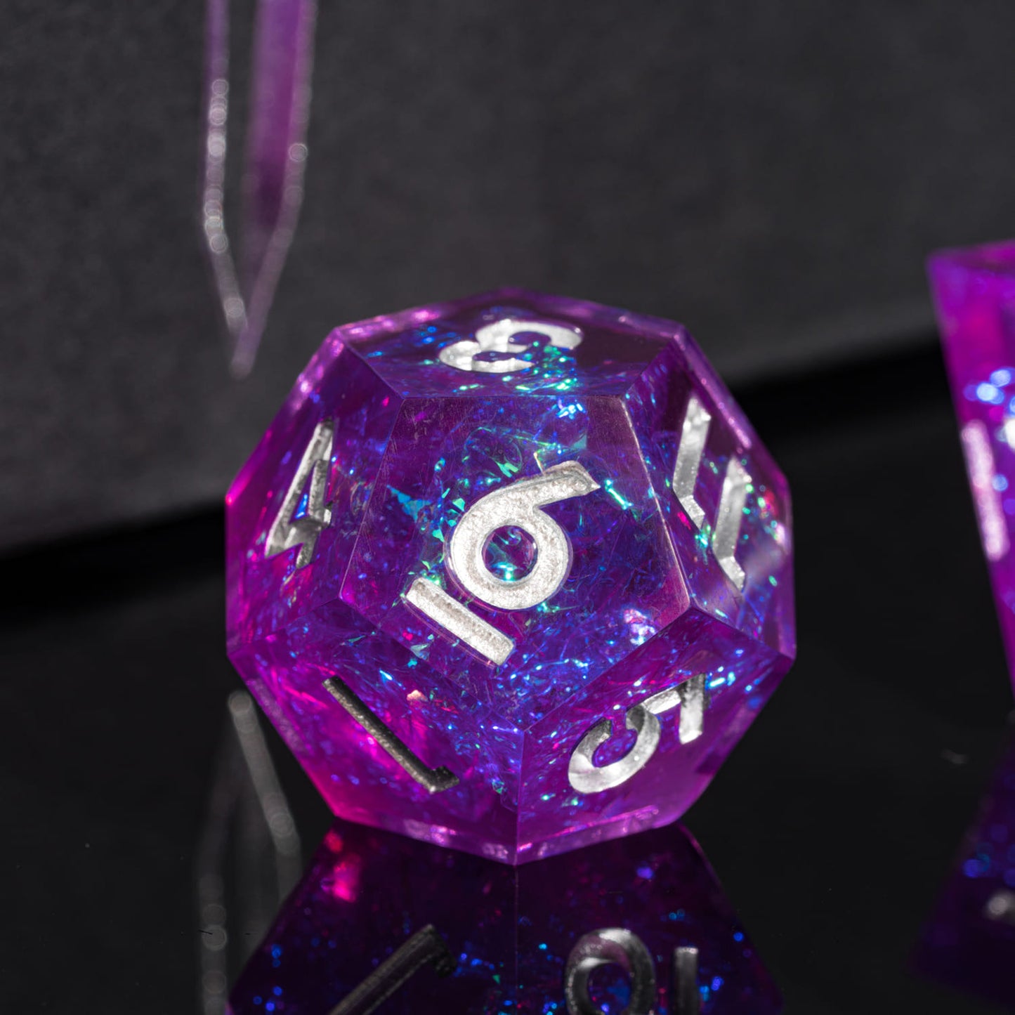 Violet Beam D20 closeup with silver numbering and sparkly violet resin on reflective black surface
