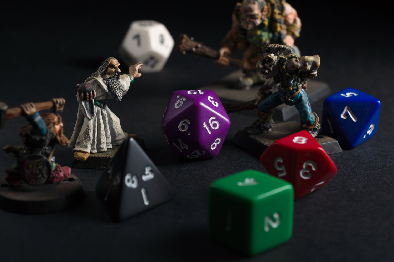 A scattering of DnD dice and TTRPG miniatures at a gaming table