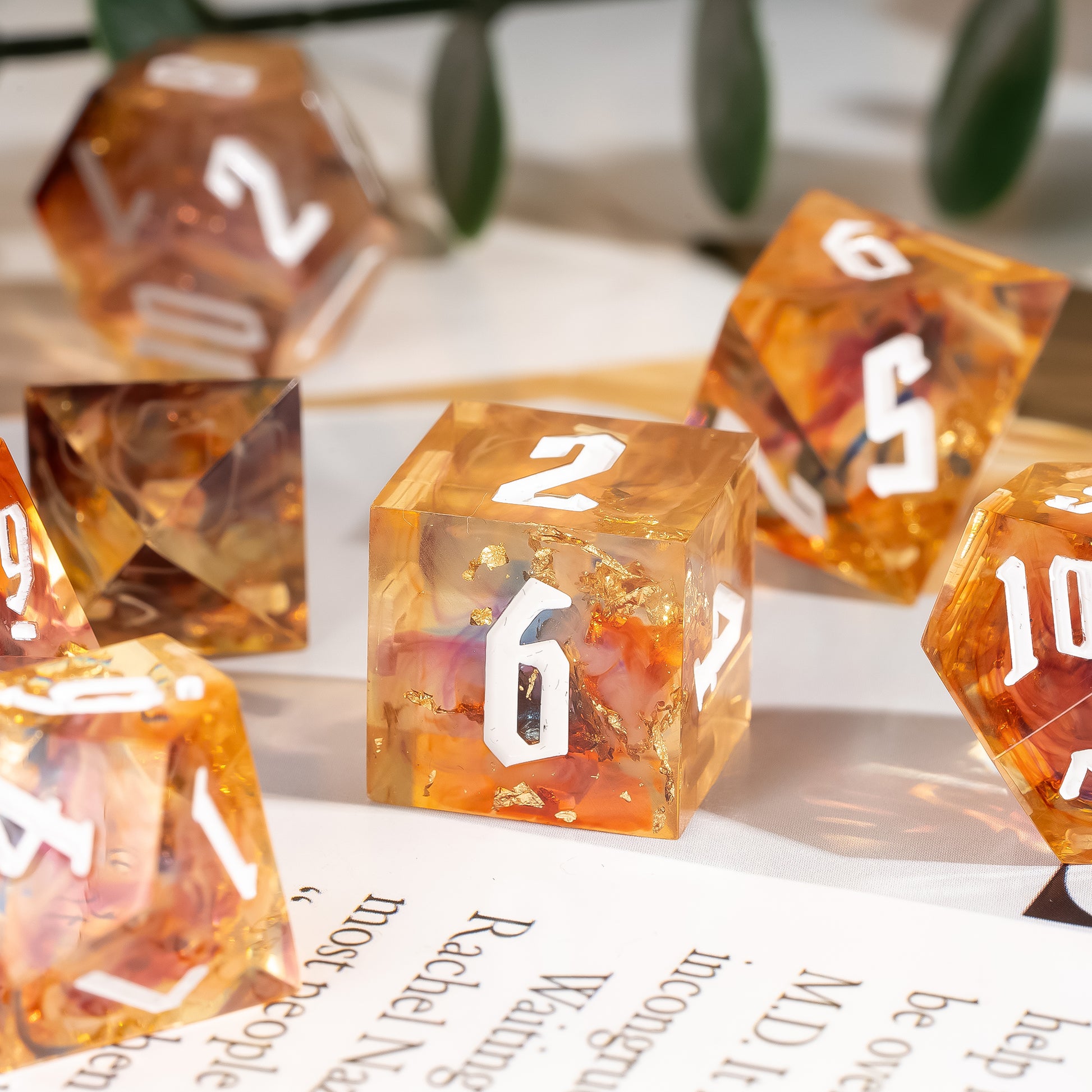 Close-up of the Aether Shards Sharp Edge Dice Set D6 featuring translucent amber resin, gold foil inclusions, and crisp white numbering