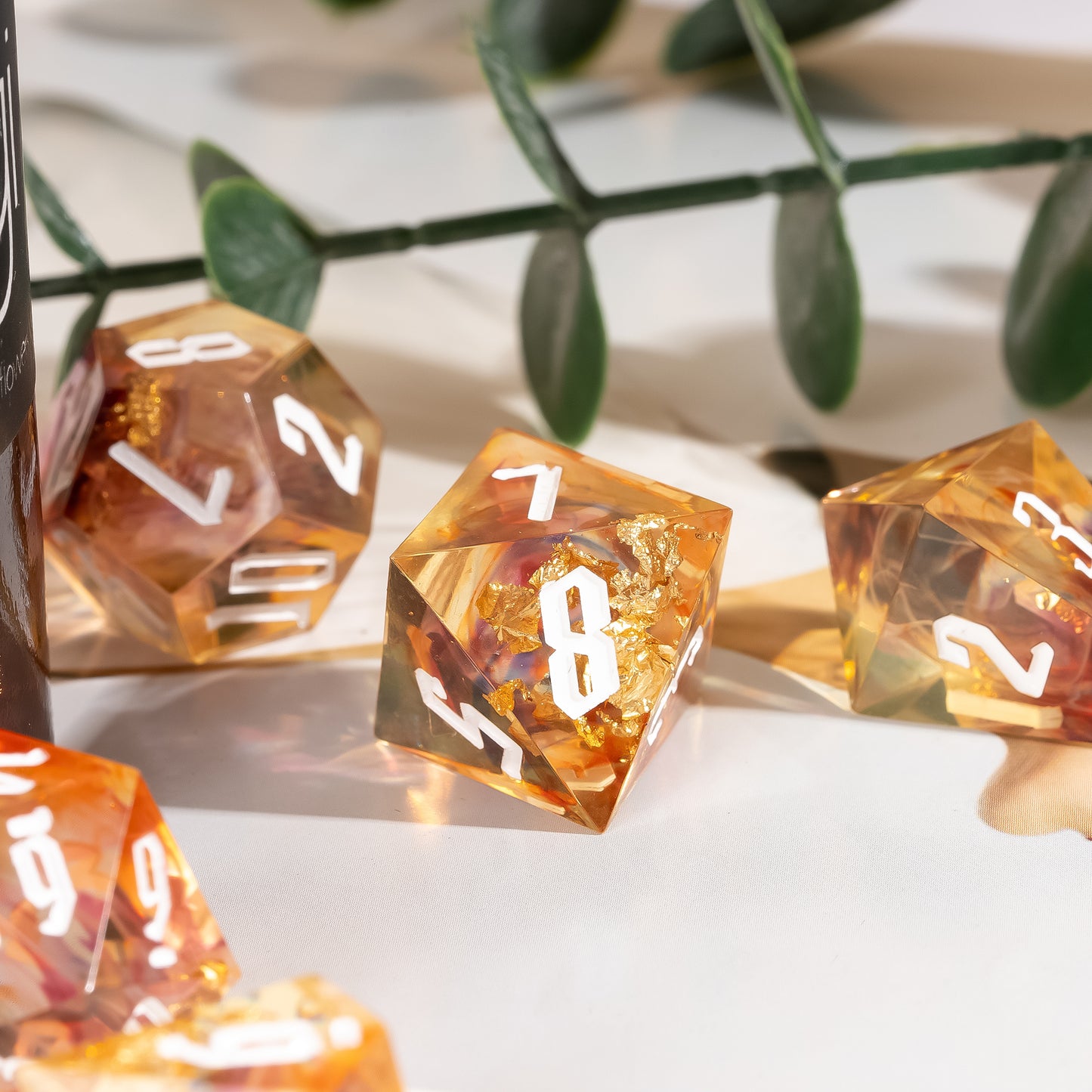 Close-up of the Aether Shards Sharp Edge Dice Set D8 featuring translucent amber resin with gold foil inclusions and white numbering