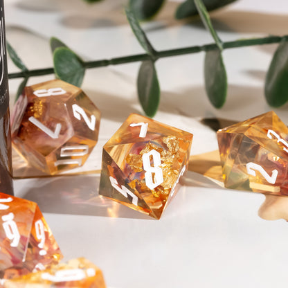 Close-up of the Aether Shards Sharp Edge Dice Set D8 featuring translucent amber resin with gold foil inclusions and white numbering