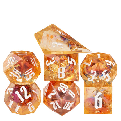 Aether Shards Sharp Edge Dice Set stacked display featuring translucent amber resin dice with gold foil inclusions and white numbering