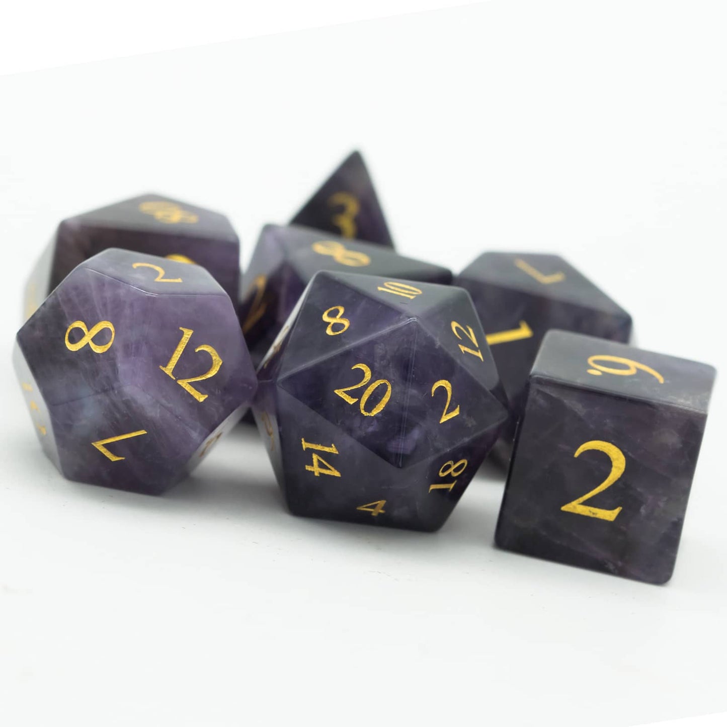 Pile of Amethyst Essence Stone Dice Set with natural purple gemstone finish and gold inking for DnD & RPG play
