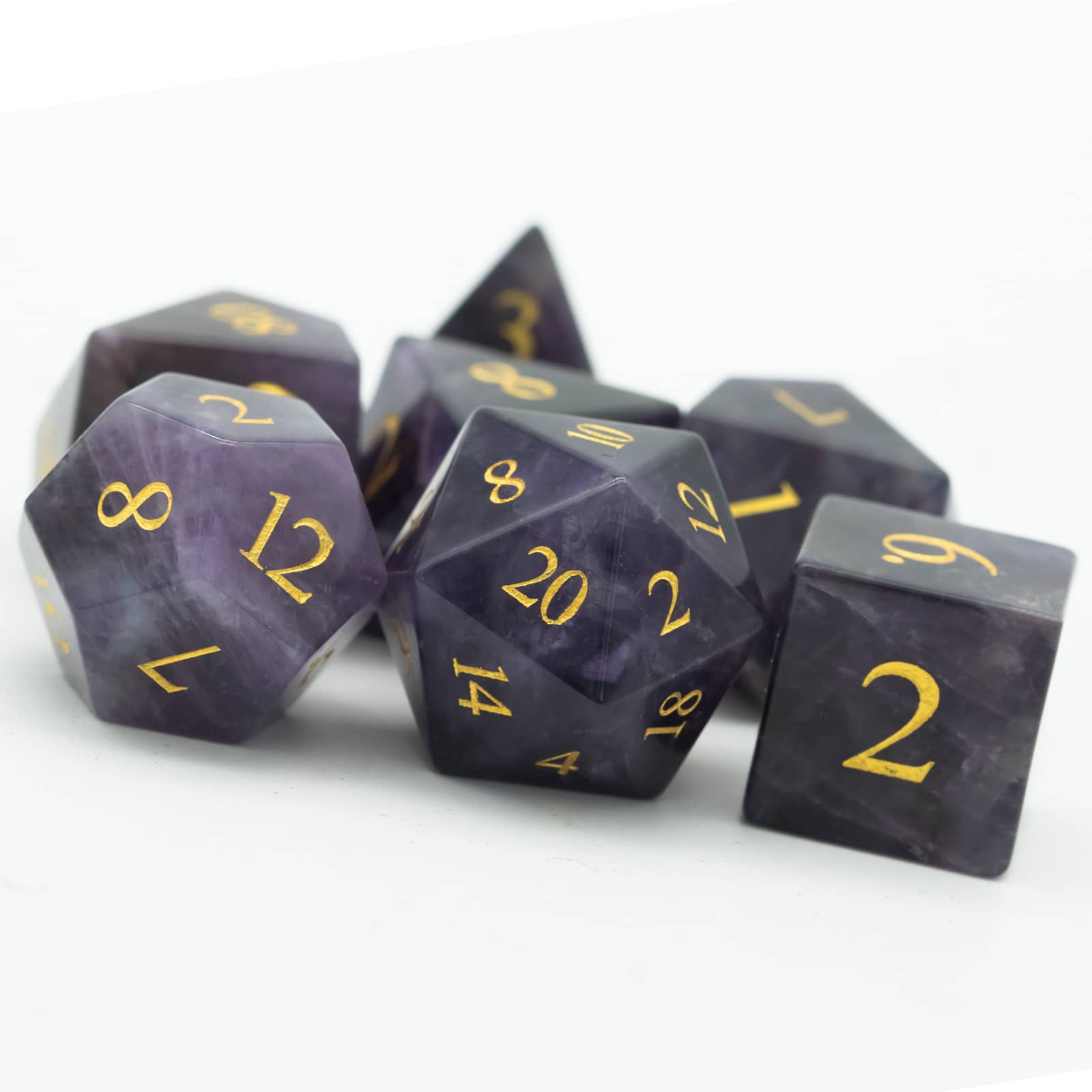 Pile of Amethyst Essence Stone Dice Set with natural purple gemstone finish and gold inking for DnD & RPG play