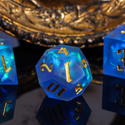 Close up of Azure Abyss D20 in blue resin with gold numbers and glowing teal swirls