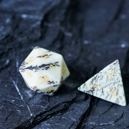 Close-up of Birch Stonework Stone Dice D20 and D4 with golden numbers on black marble surface