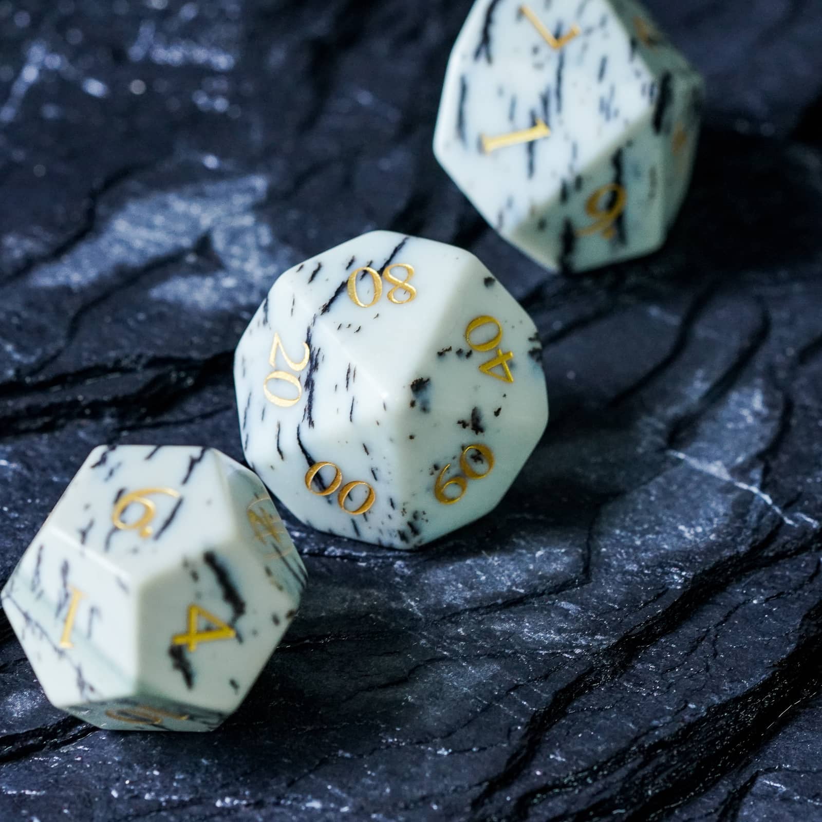 Birch Stonework Stone Dice Set D10 and D20 on dark rock texture highlighting intricate details