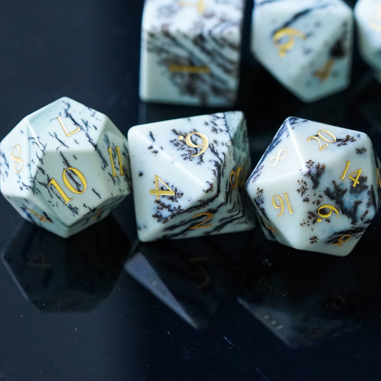 Close-up of Birch Stonework Stone Dice Set on reflective black surface with gold numbers and marble veining