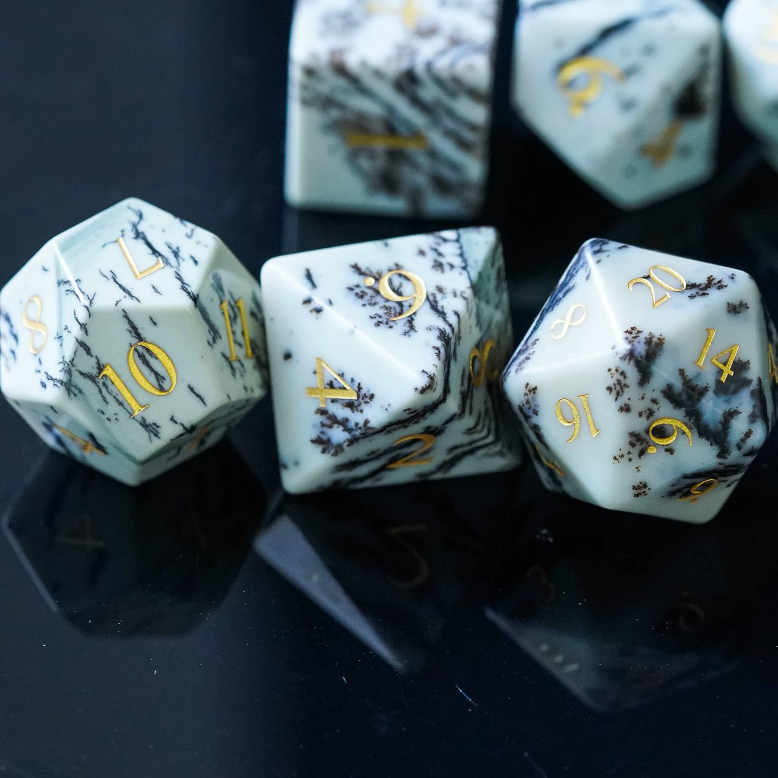 Close-up of Birch Stonework Stone Dice Set on reflective black surface with gold numbers and marble veining