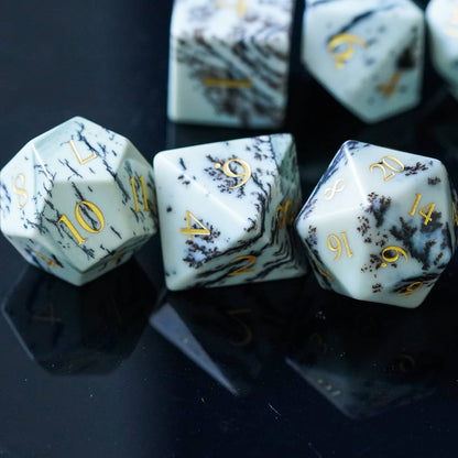 Close-up of Birch Stonework Stone Dice Set on reflective black surface with gold numbers and marble veining