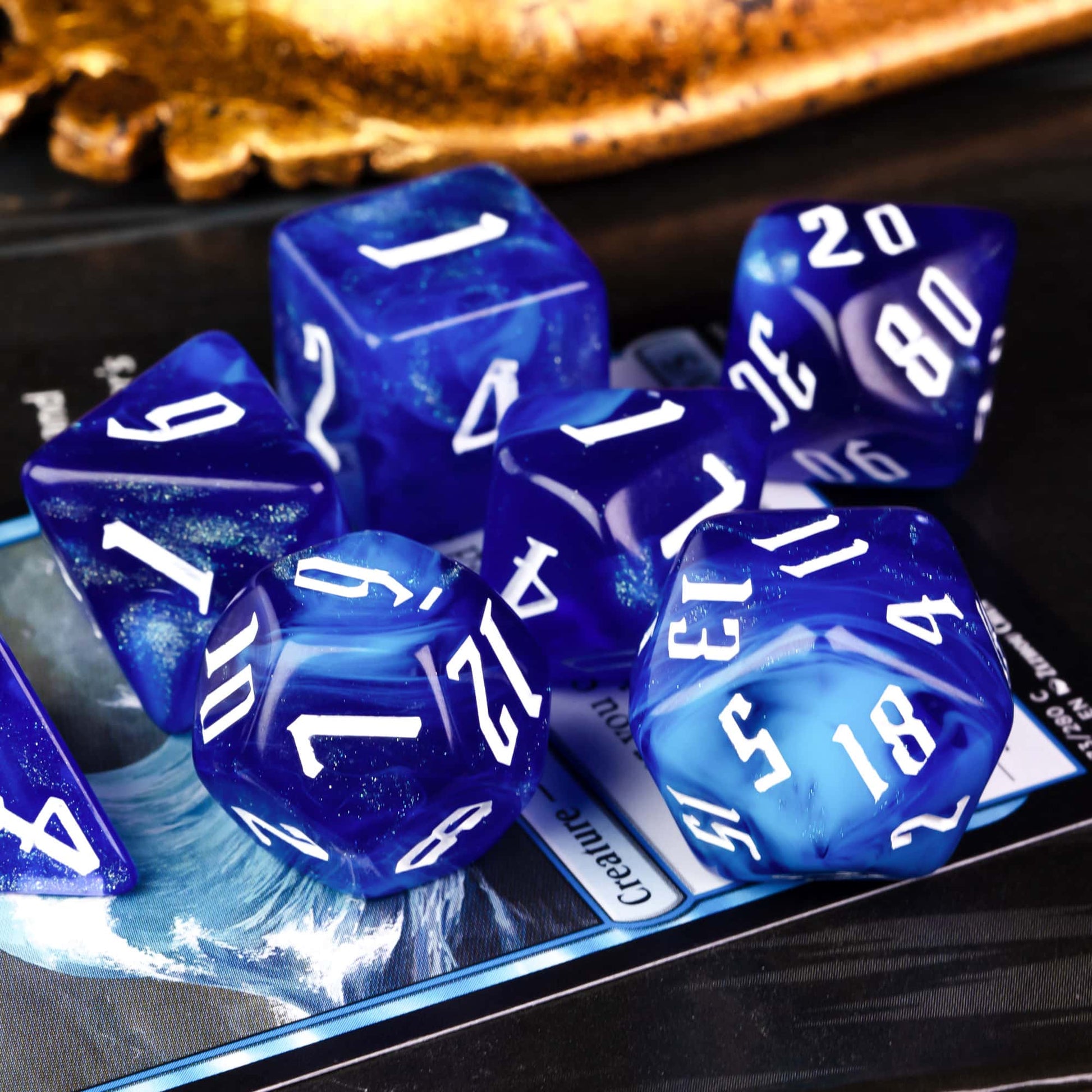 Blue Sapphire polyhedral dice set with shimmering blue resin and white numbers angled view