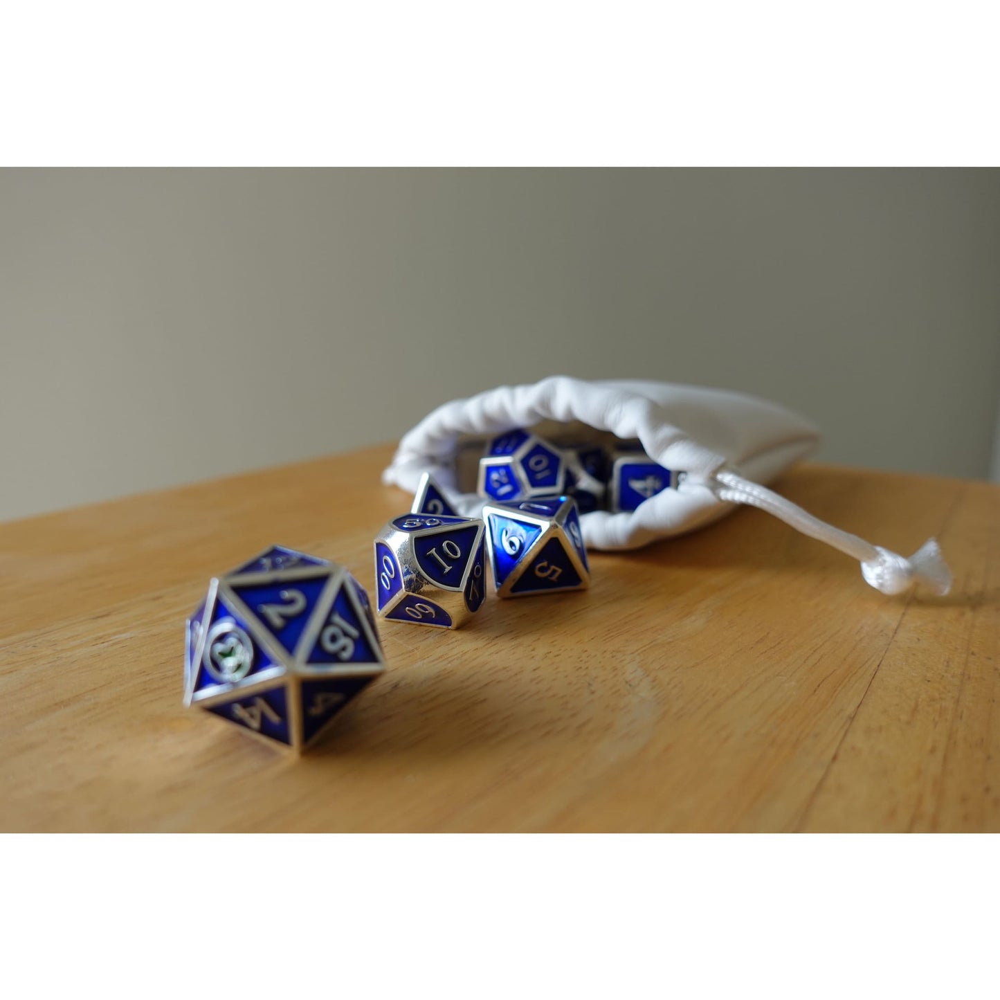 Blue & silver Bob World Builder dice spilling out of white drawstring bag on wooden table