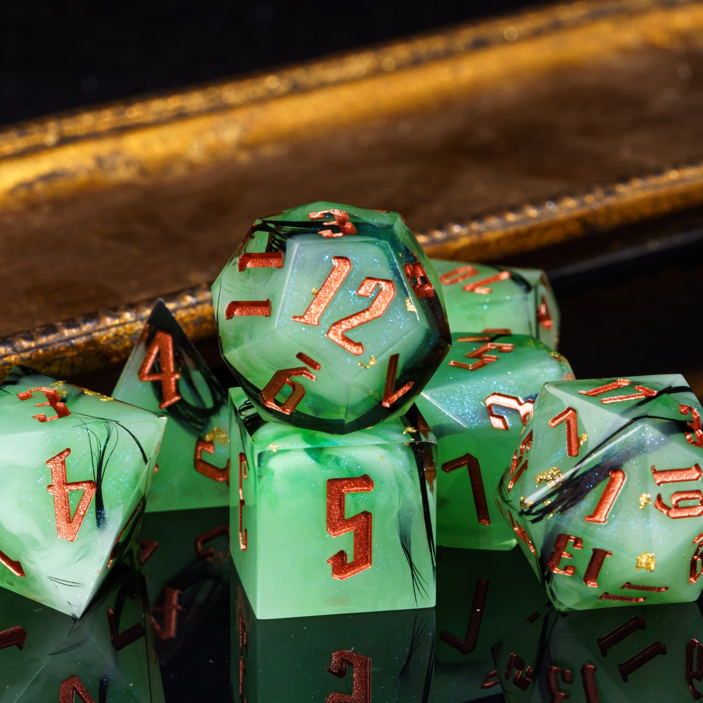 Bog Hag Sharp Edge Dice Set arranged on reflective surface showing green resin and gold foil