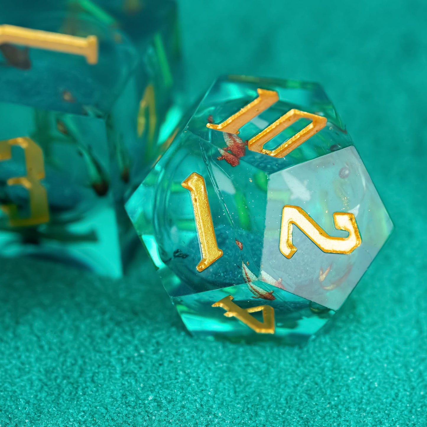 Close up of Celestial Reef D10 with teal resin and gold numbering