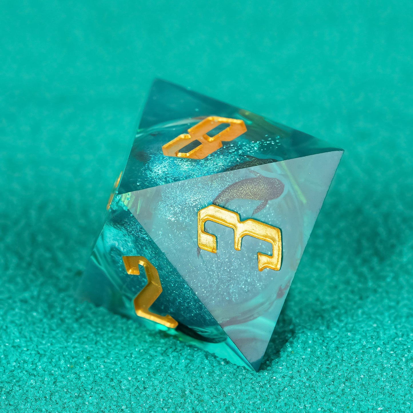Celestial Reef sharp edge D4 in teal resin with gold numbering on textured background