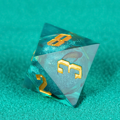 Celestial Reef sharp edge D4 in teal resin with gold numbering on textured background