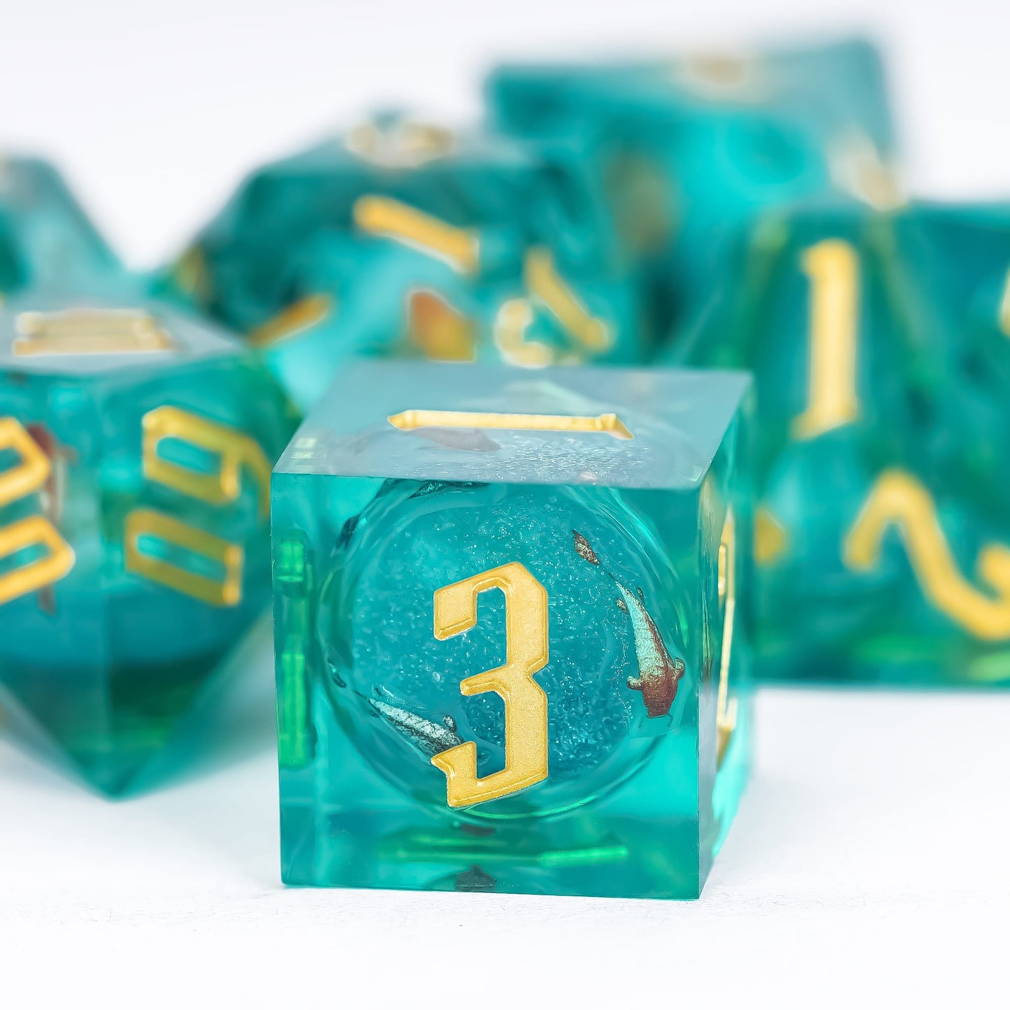 Close up of Celestial Reef D6 showing teal resin, gold numbering and suspended inclusions