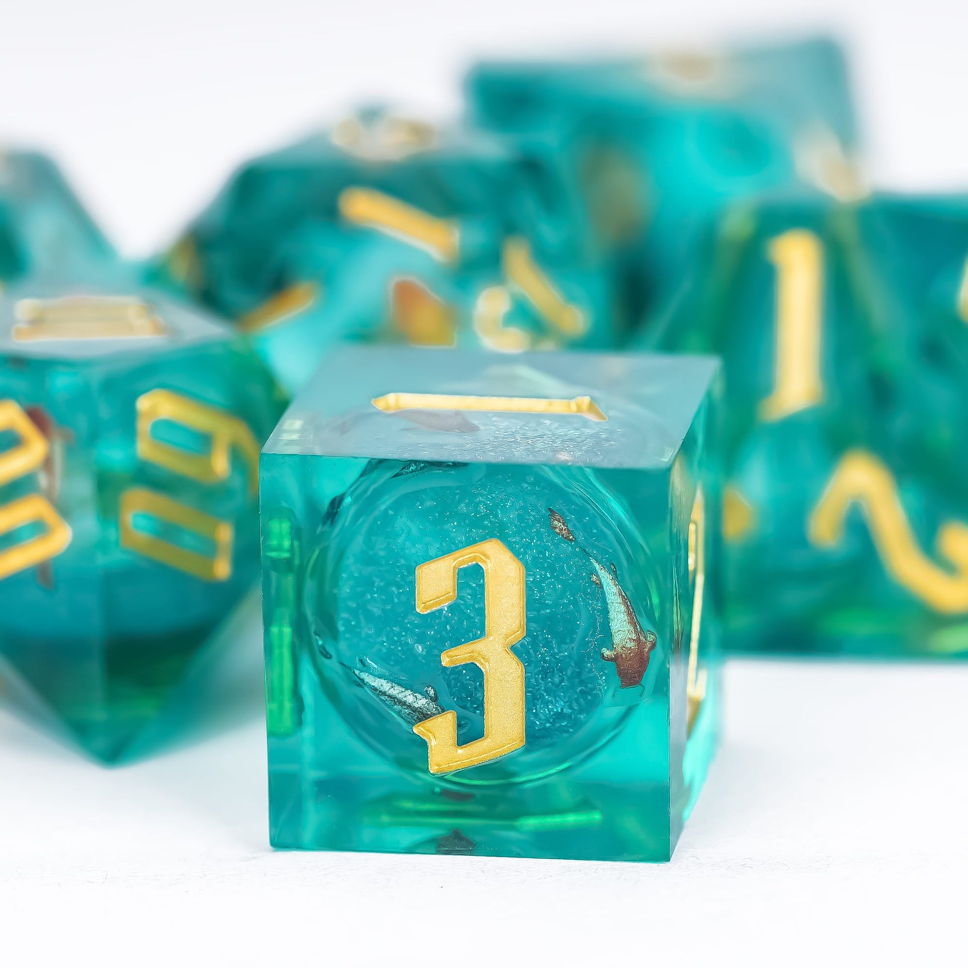 Close up of Celestial Reef D6 showing teal resin, gold numbering and suspended inclusions