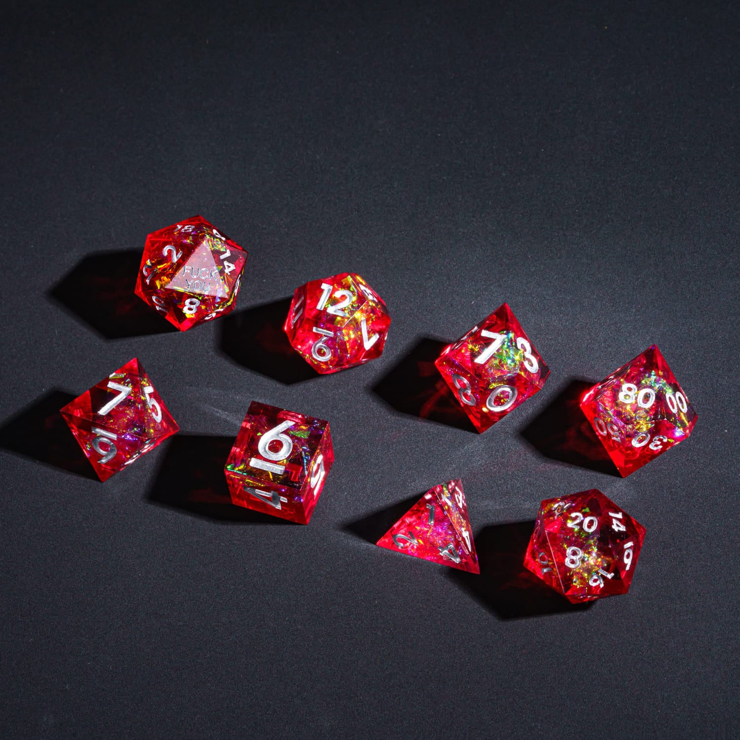 Flat lay of Chromatic Blood F*ck Me Sharp Edge Dice Set 7 piece dice collection for DnD & DnD 5e