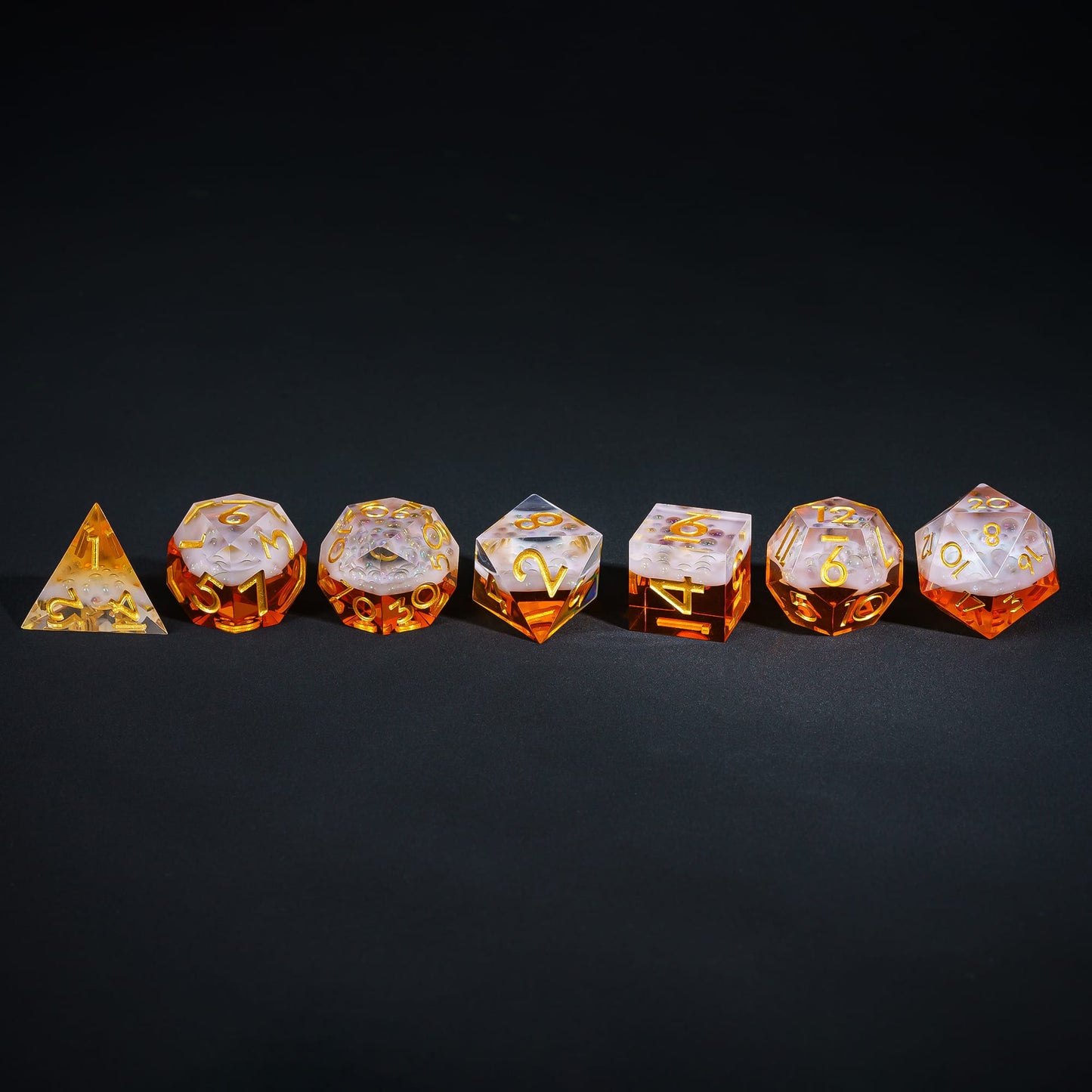 Crisp Brew Sharp Edge Dice Set lined up on black background with amber resin and gold numbering for DnD