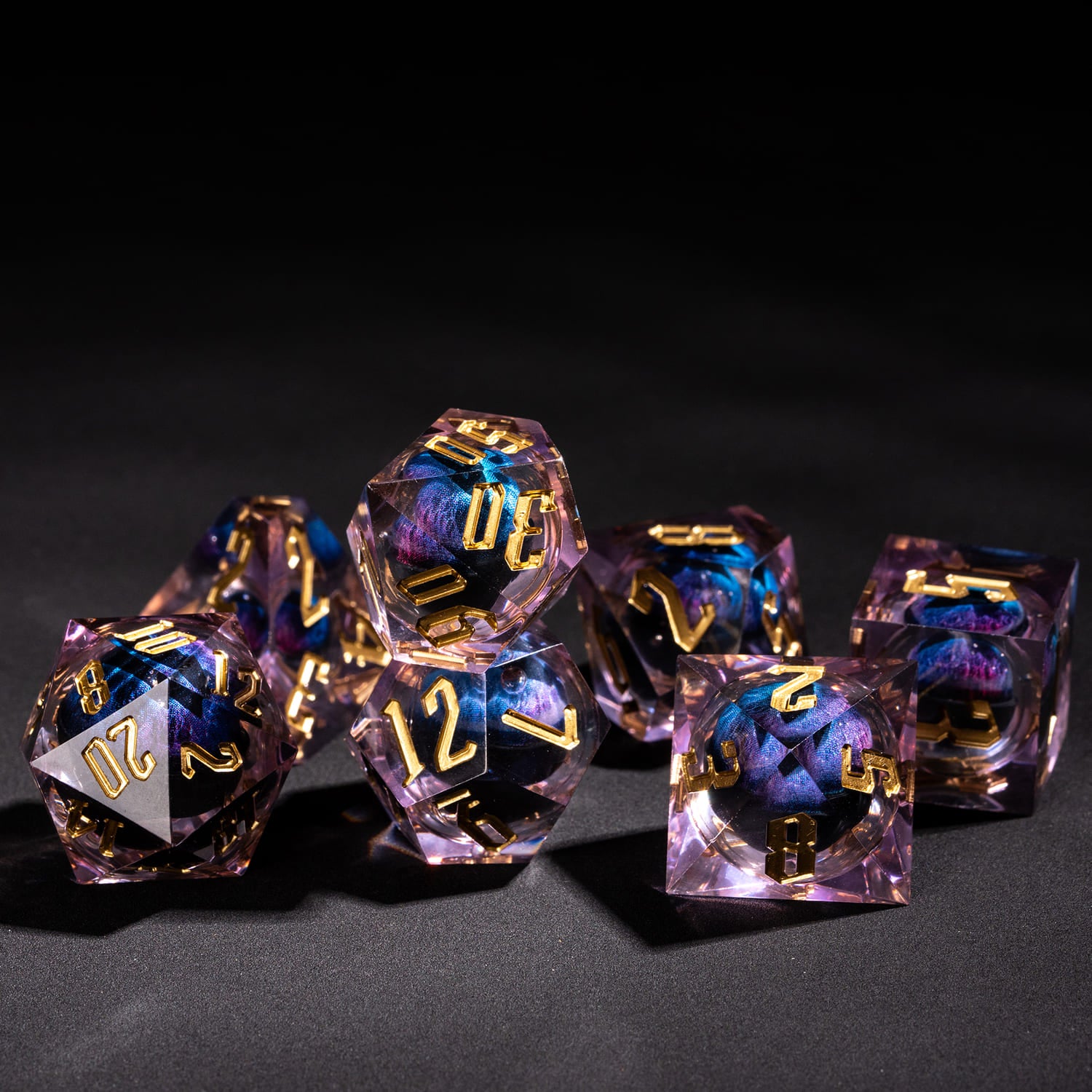 Dragon Eye Purple sharp edge dice set arranged on dark surface showing translucent purple resin and gold numbering