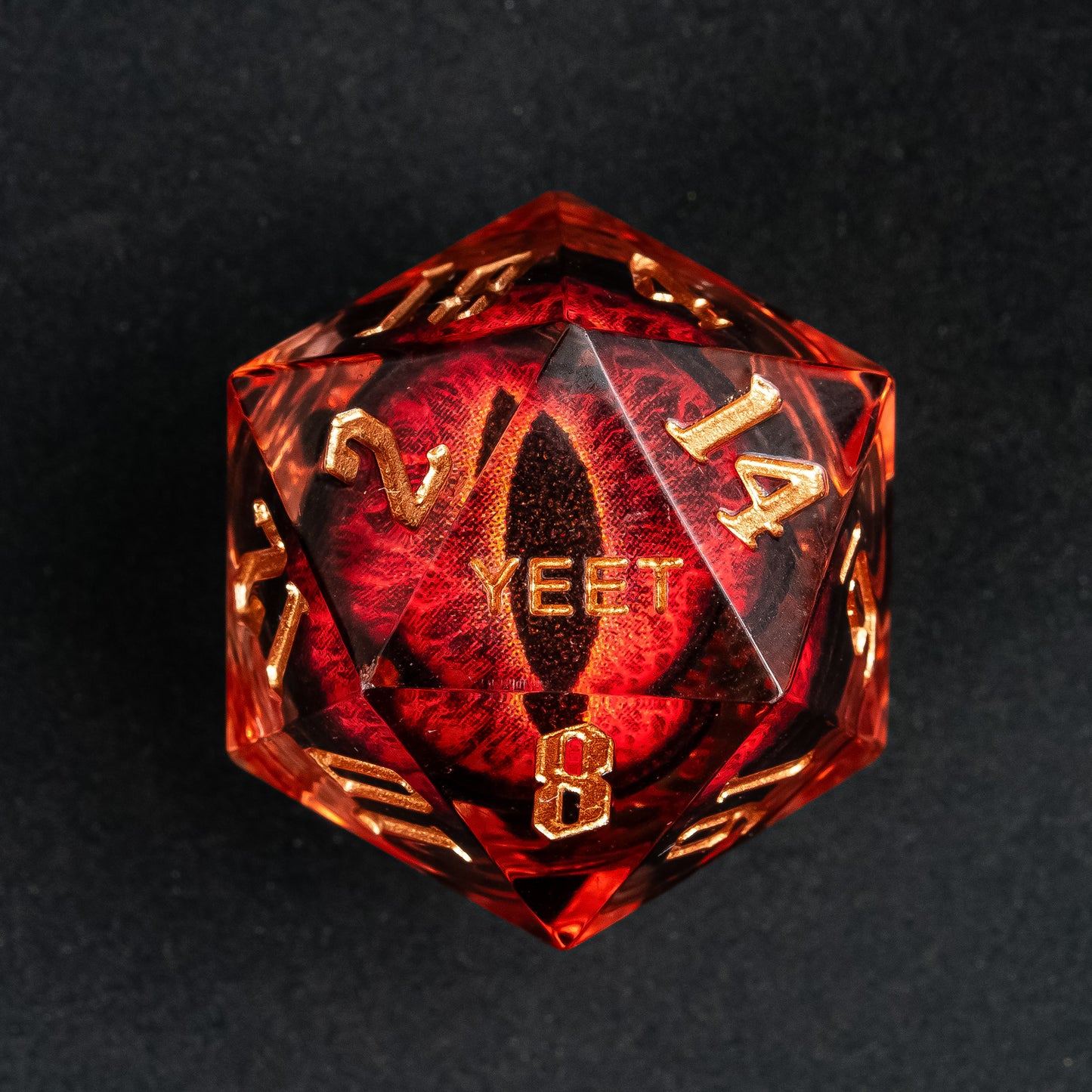 Close-up of the D20 from Dragon Eye (Red) Yeet Sharp Edge Dice Set showing gold numbering and embedded red eye design