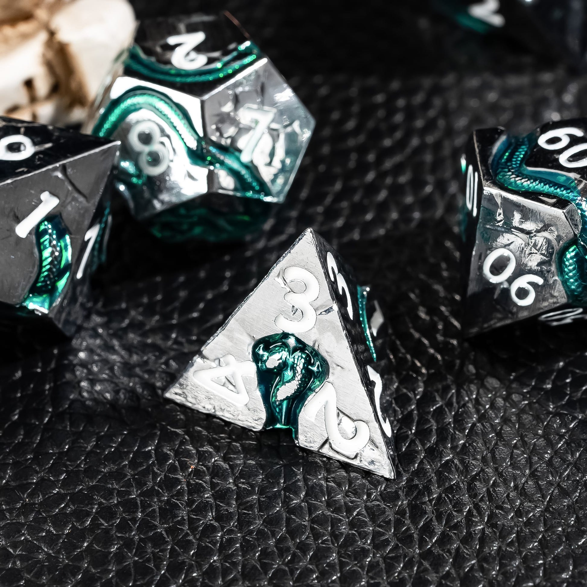 Emerald Serpent metal D4 close up with engraved serpent and emerald green detailing