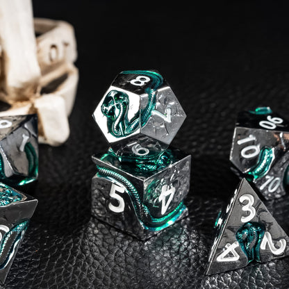 Detailed view of stacked Emerald Serpent metal dice with silver metal and green inlay