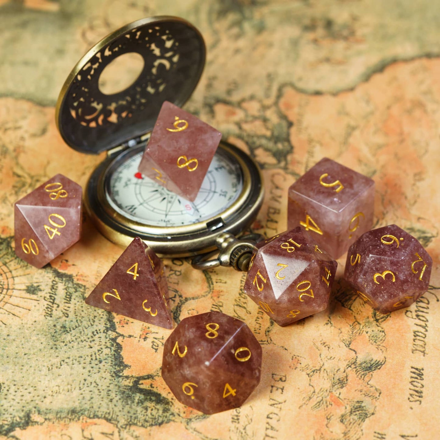 Ember Rose stone dice set from Fabled Crystals series displayed with antique compass on fantasy map for DnD & TTRPG