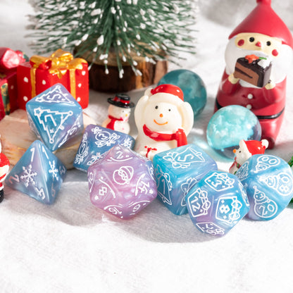 Pink and blue Festive Fate holiday DnD dice set with Christmas themed engravings beside mini snowmen and gifts