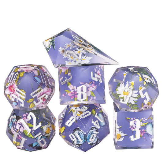 Stacked display of Floral Eclipse Sharp Edge Dice Set 7 piece lavender resin dice with floral and butterfly design for DnD
