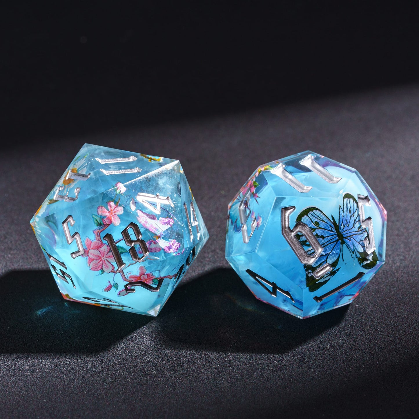Two Floral Mist Sharp Edge D20 dice close-up, blue resin with floral design for Dungeons & Dragons