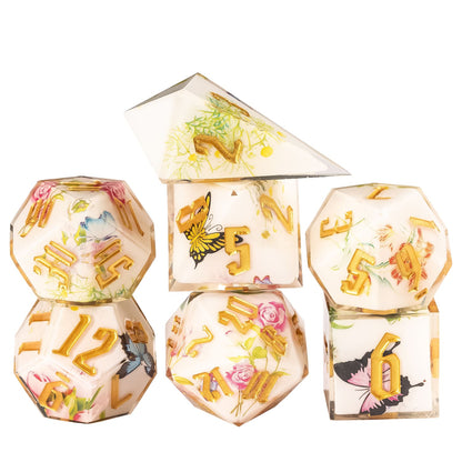 Floral Radiance Sharp Edge Dice Set stacked display featuring ivory resin dice with floral and butterfly designs and metallic gold numbers