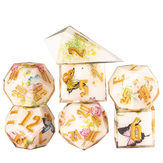 Floral Radiance Sharp Edge Dice Set stacked display featuring ivory resin dice with floral and butterfly designs and metallic gold numbers