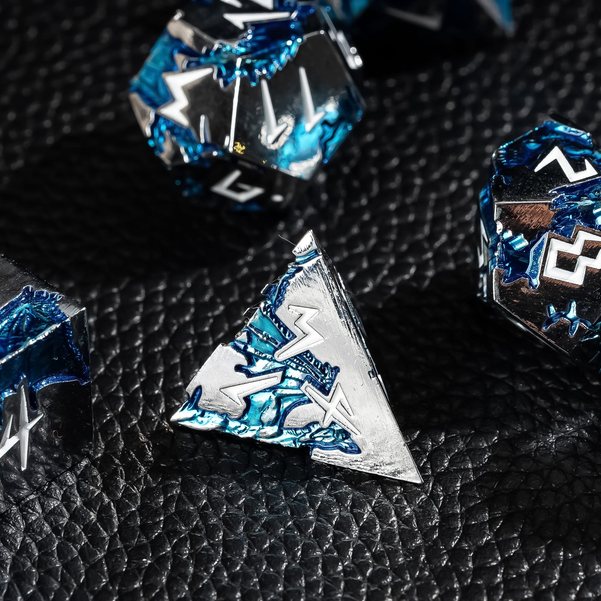 Close-up of Frost Tide Dragon D4 metal dice with silver finish and blue wave detailing