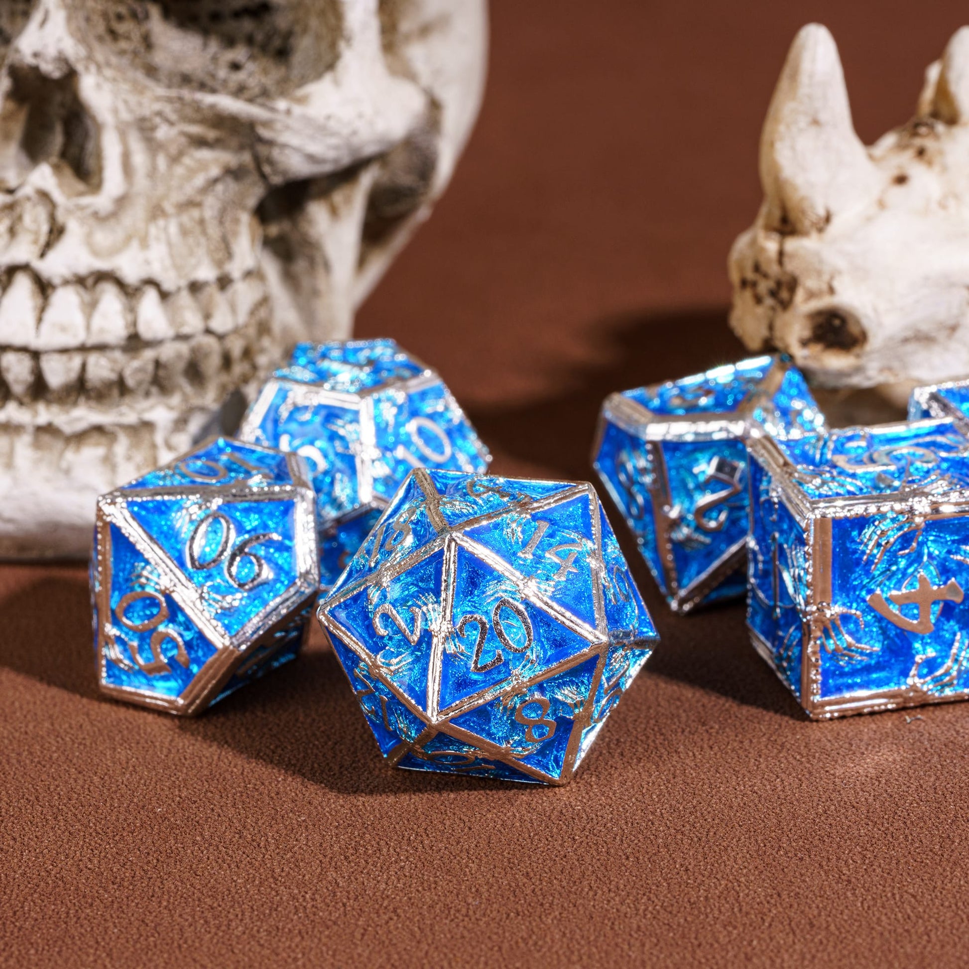 Frosted Crypt Metal Dice Set shimmering blue and silver D20 with skull background